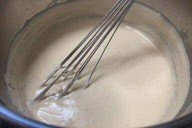 Béchamelsauce beim Kochen mit Schneebesen im Topf - béchamel with a whisk in a pot