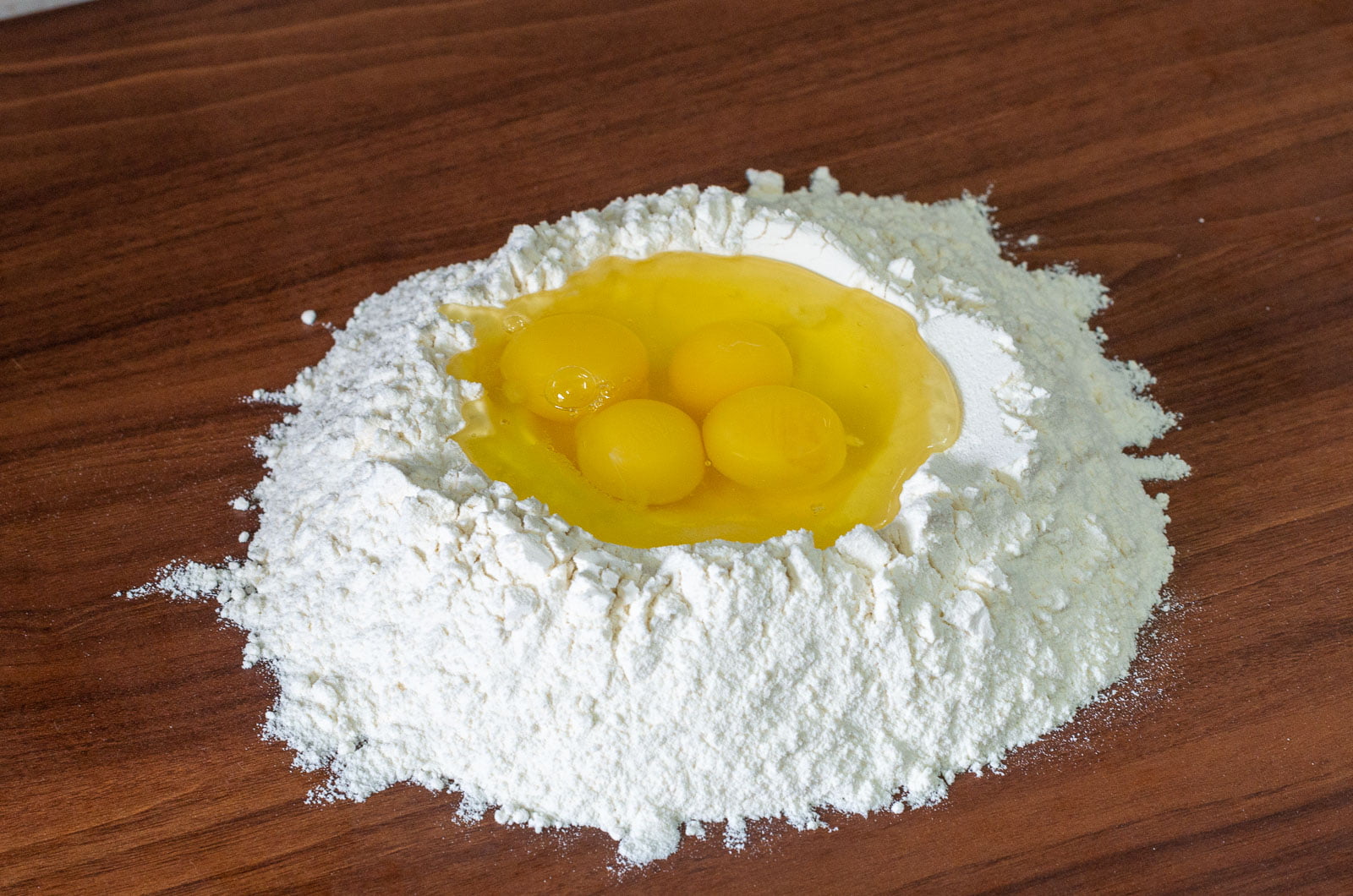 Eier in einer Mulde aus Mehl auf Arbeitsfläche zum Kneten