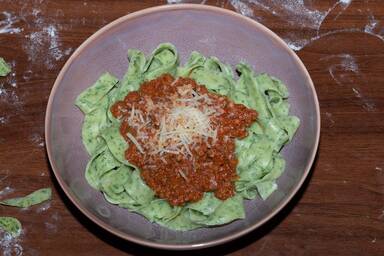 Tagliatelle verde con ragu alla bolognese in einer lila Schüssel - a purple bowl