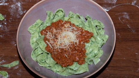 Tagliatelle verde con ragu alla bolognese in einer lila Schüssel - a purple bowl