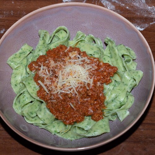 Tagliatelle verde con ragu alla bolognese in einer lila Schüssel - a purple bowl