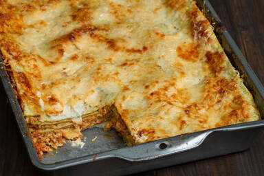 Lasagne verdi alla Bolognese in einer Auflaufform, ein Stück herausgeschnitten - Lasagne verdi alla Bolognese in a baking try, one piece cut out