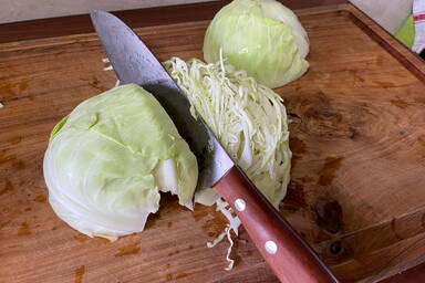 Schneiden des Kohlkopfes auf einem Schneidebrett - Cutting the cabbage on a chopping board