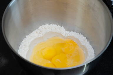 Eier in Mehlmulde in einer Rührschüssel - Eggs in a flour trough in a mixing bowl