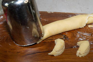 Schneiden der Teigrolle der Burgenländer Kipferl mit einem runden Ausstecher in Halbmonde - Cutting Burgenland Kipferl with a round cutter from a roll of dough