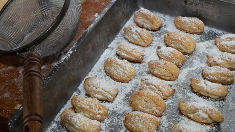 Burgenländer Kipferl mit Puderzucker bestreut, neben einem Metallsieb was zum bestäuben verwendet wurde - Burgenländer Kipferl dusted with Icing sugar. The metal sieve used is lying next to it