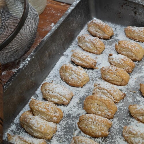 Burgenländer Kipferl mit Puderzucker bestreut, neben einem Metallsieb was zum bestäuben verwendet wurde - Burgenländer Kipferl dusted with Icing sugar. The metal sieve used is lying next to it