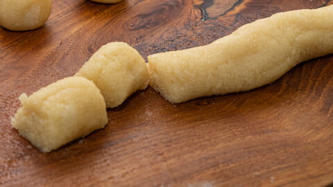 Selbstgemachtes Marzipan in Rollenform auf einem Brett - homemade marzipan dough shaped as a string on a board