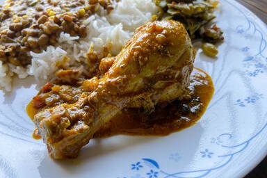 Kozhi Curry auf einem Teller mit Reis, Dal und Bohnengemüse - Kozhi Curry on a plate next to rice, dal and green beans