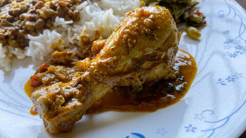 Kozhi Curry auf einem Teller mit Reis, Dal und Bohnengemüse - Kozhi Curry on a plate next to rice, dal and green beans