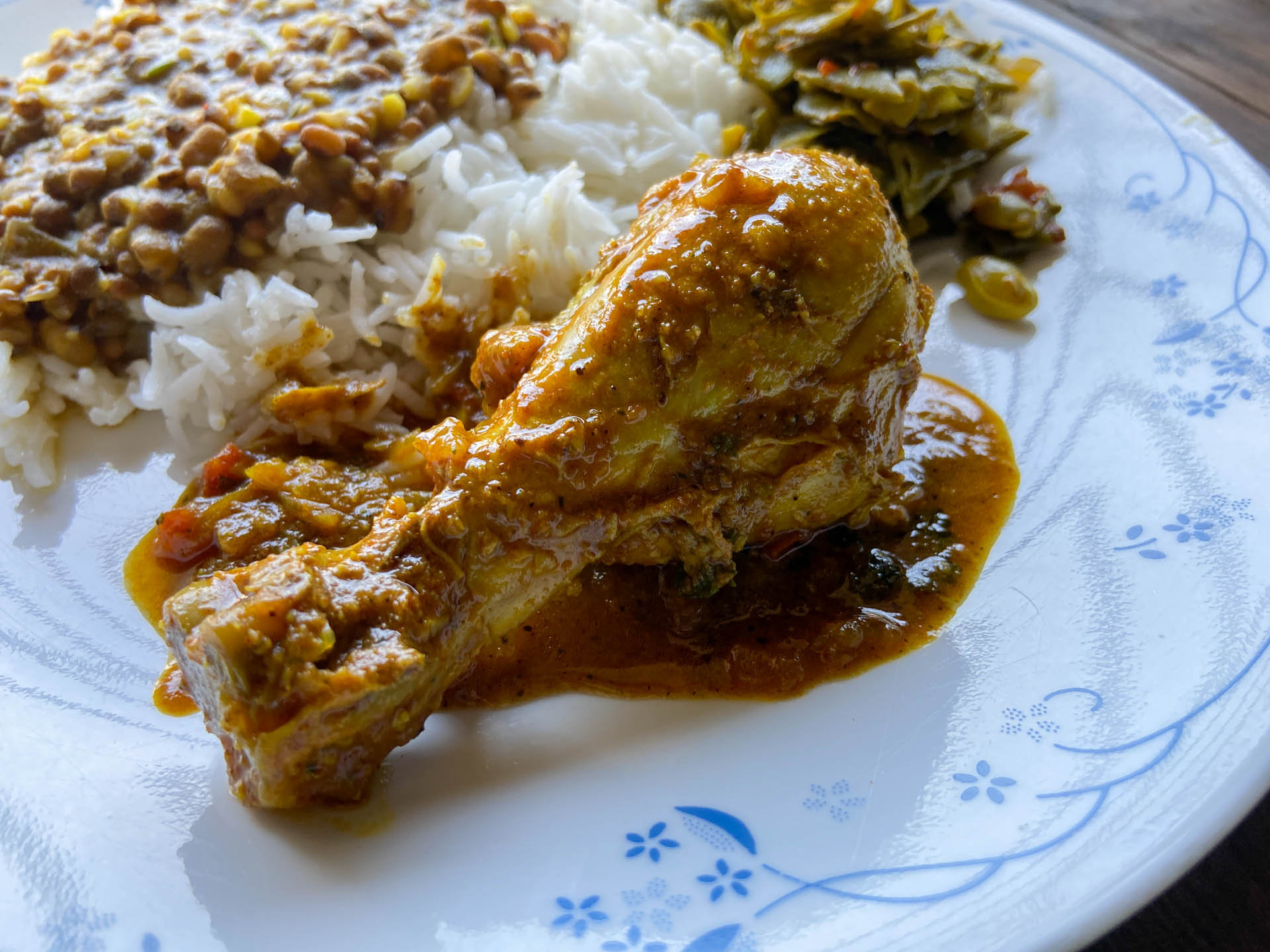 Kozhi Curry auf einem Teller mit Reis, Dal und Bohnengemüse - Kozhi Curry on a plate next to rice, dal and green beans
