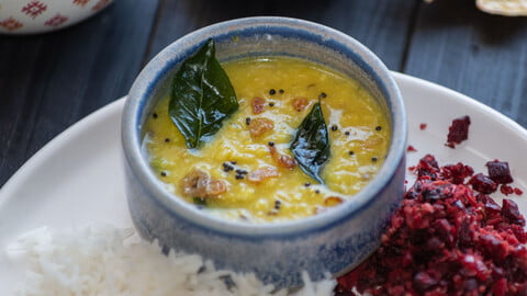 Parippu Curry in einer kleinen Schale neben Reis und Rote Beete Thoran auf einem Teller - Parippu Curry in a small bowl next to rice and beetroot thoran on a plate