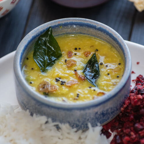 Parippu Curry in einer kleinen Schale neben Reis und Rote Beete Thoran auf einem Teller - Parippu Curry in a small bowl next to rice and beetroot thoran on a plate