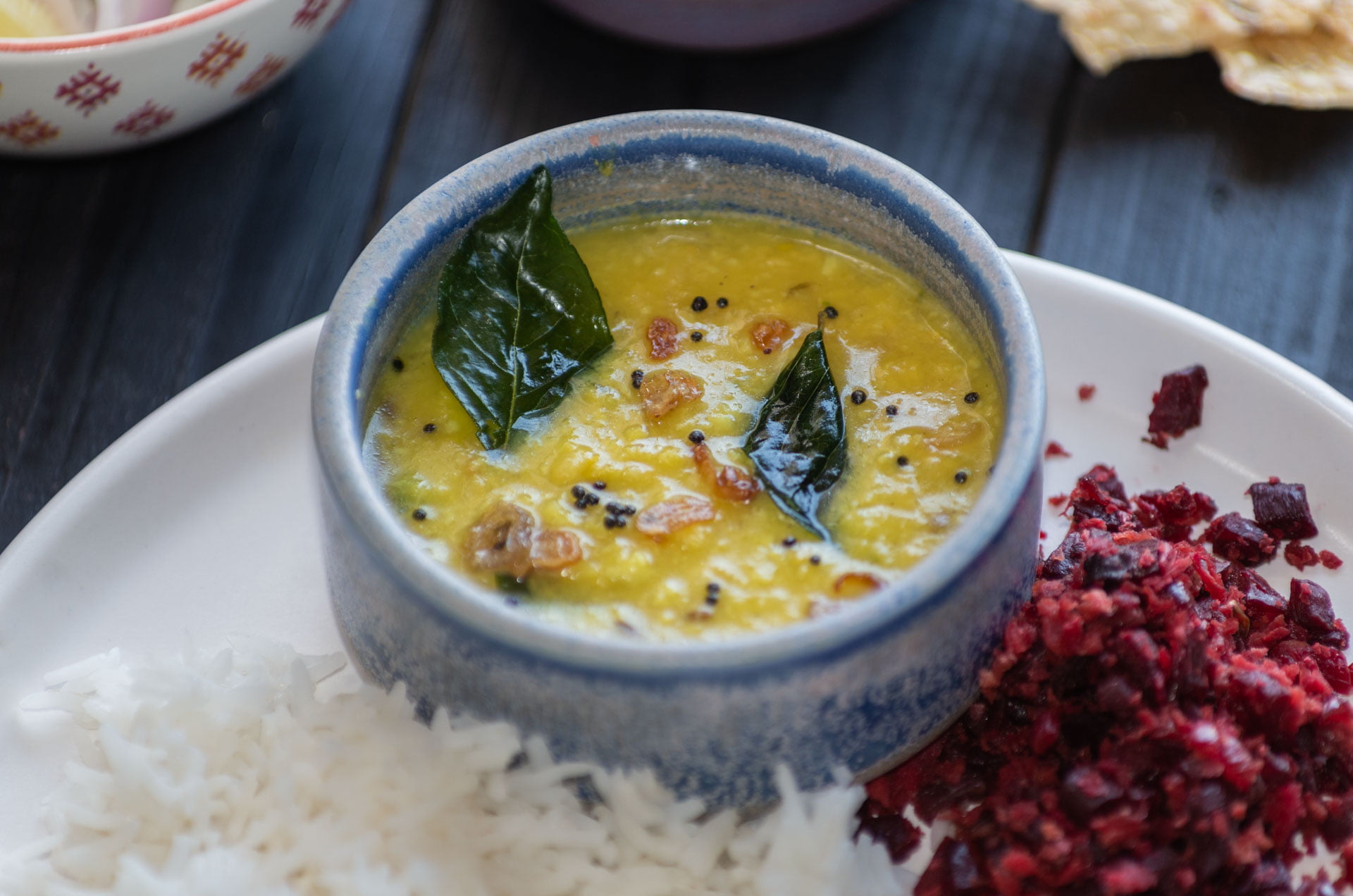 Parippu Curry in einer kleinen Schale neben Reis und Rote Beete Thoran auf einem Teller - Parippu Curry in a small bowl next to rice and beetroot thoran on a plate