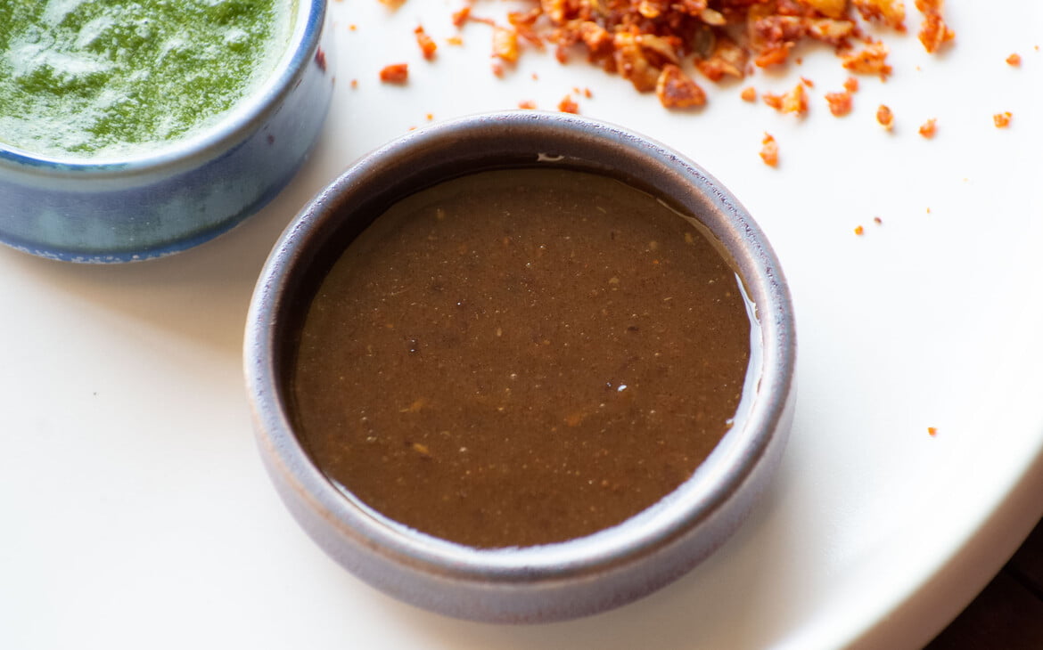 Indisches süßes Chutney in einer kleinen Schale, dahinter grünes Chutney und trockenes Knoblauchchutney - Indian sweet chutney in a small bowl, in the background green chutney and dry garlic chutney