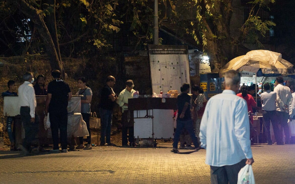 Typische Szene in Mumbai am Abend: mehrere Streetfood- (Chaat-) Händler nebeneinander mit Kunden - typical scene in Mumbai in the evening: three streetfood vendors (chaatwalas) next to each other with their customers