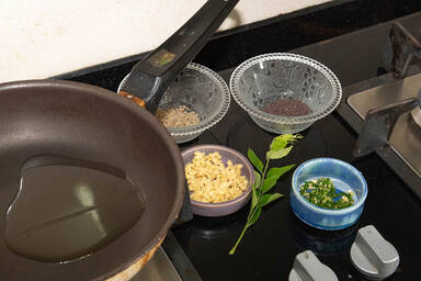 Zutaten für eine Baghar neben der Bratpfanne, vor dem Kochen abgemessen und in Schälchen gefüllt - Ingredients for a baghar next to the frying pan, measured out before cooking and put in small bowls