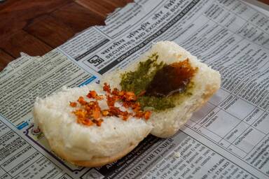 Chutneys im Pav (Brötchen) für Vada Pav auf einer Zeitung - Chutneys in the pav, a typical Indian roll, for vada pav on top of a newspaper