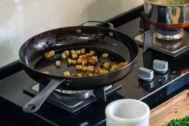 Knusprig gebratene Brotwürfel in einer Pfanne - Crispy fried bread cubes in a frying pan