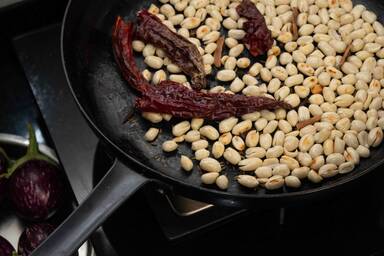 Erdnüsse und Gewürze in der Pfanne beim Rösten - Peanuts and spices in the pan while roasting